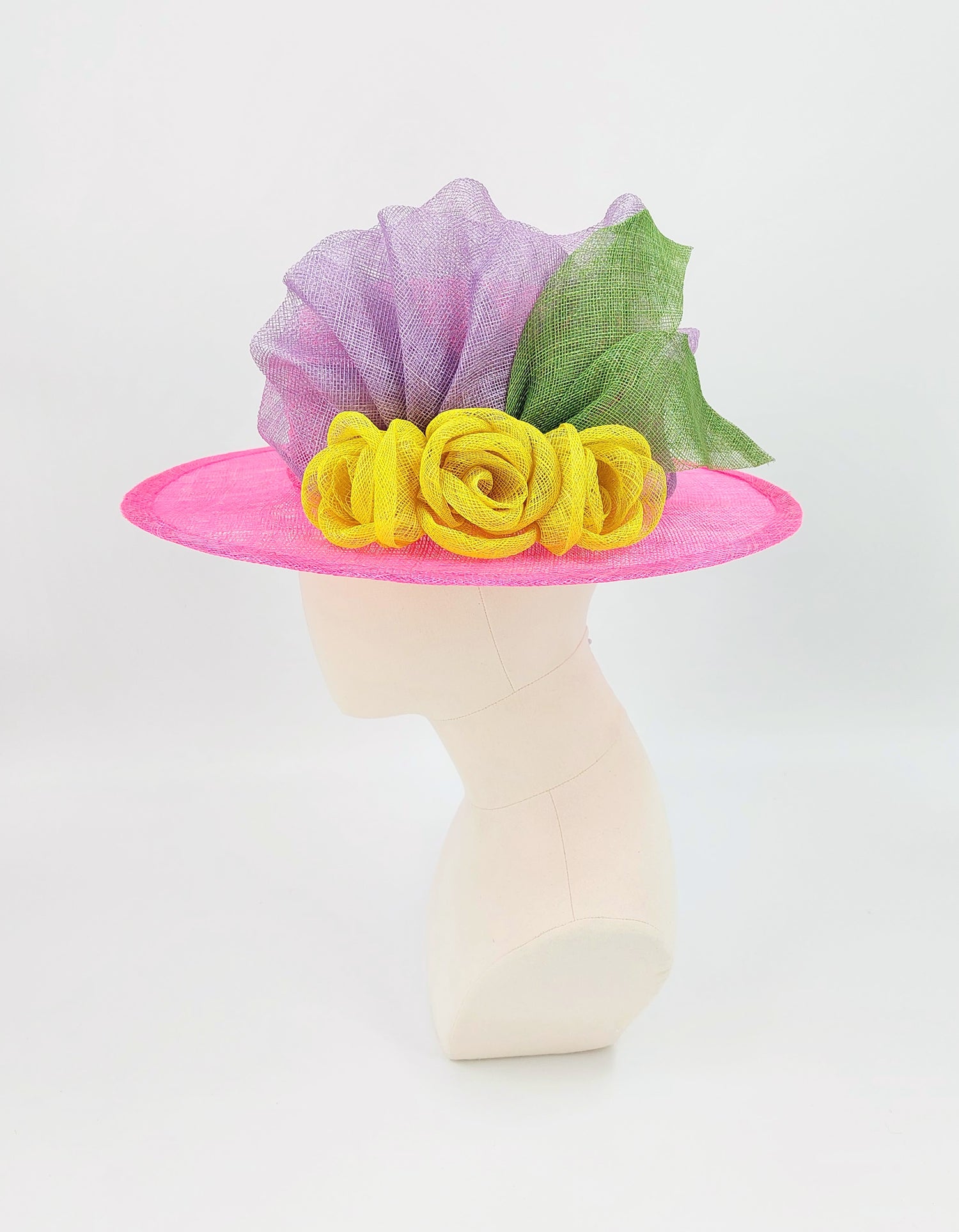 Colorful hat with pink base, yellow flowers, and purple and green accents on a mannequin head against a white background.